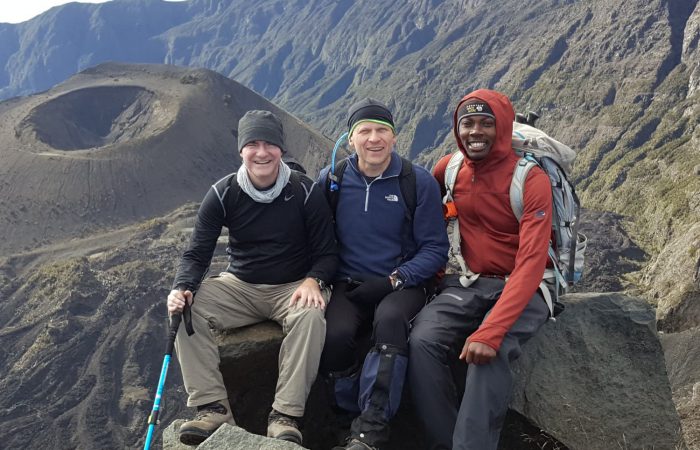 Three trekkers smiling as they climb Mt. Meru