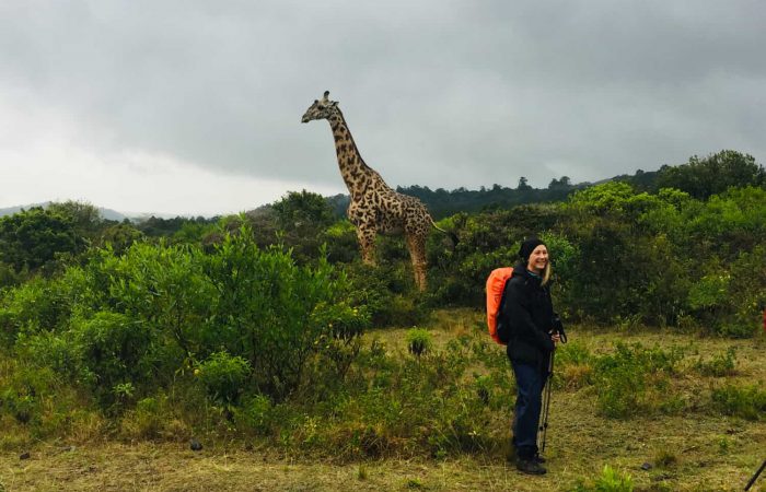 Trekker with a giraffe on the 2-day Mt. Meru trek to the Tululusia Waterfall